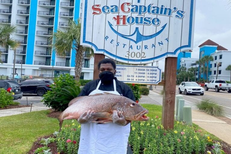 Sea Captain's House Sous Chef Derrick Sparks holidng a fish outside of the restaurant