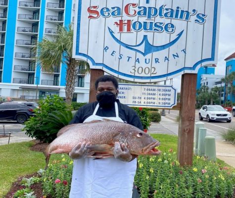 Sea Captain's House Sous Chef Derrick Sparks holidng a fish outside of the restaurant